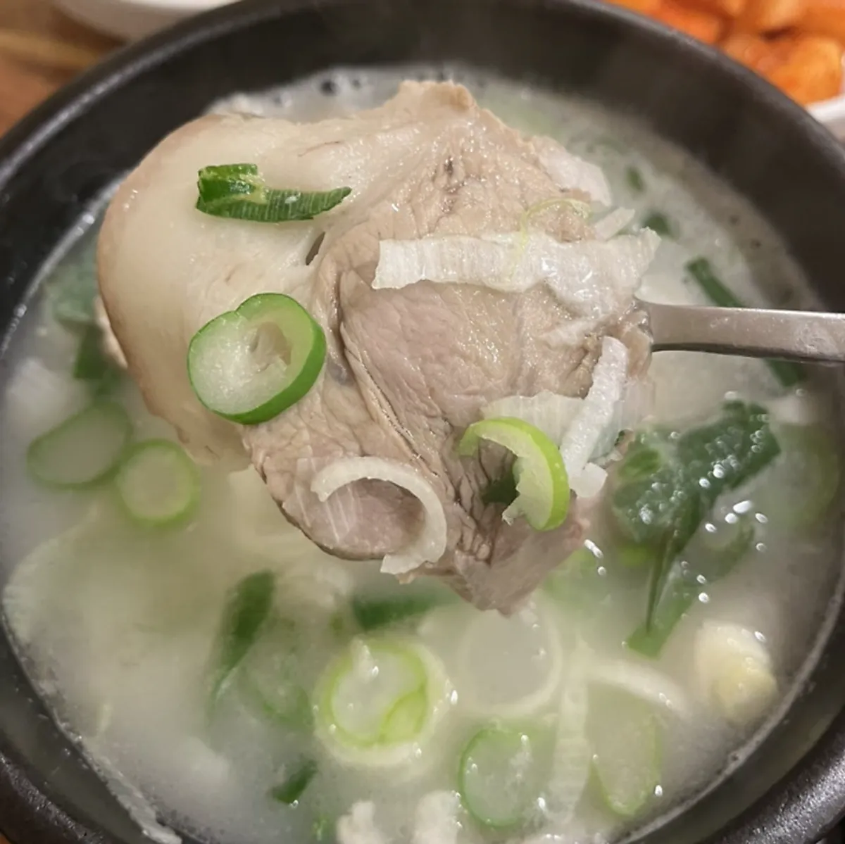 Close-up of dwaeji gukbap loaded with pork