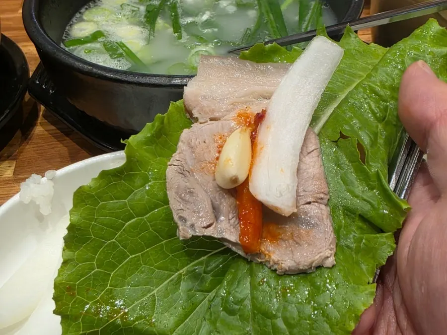 수육을 반찬과 함께 먹는 모습