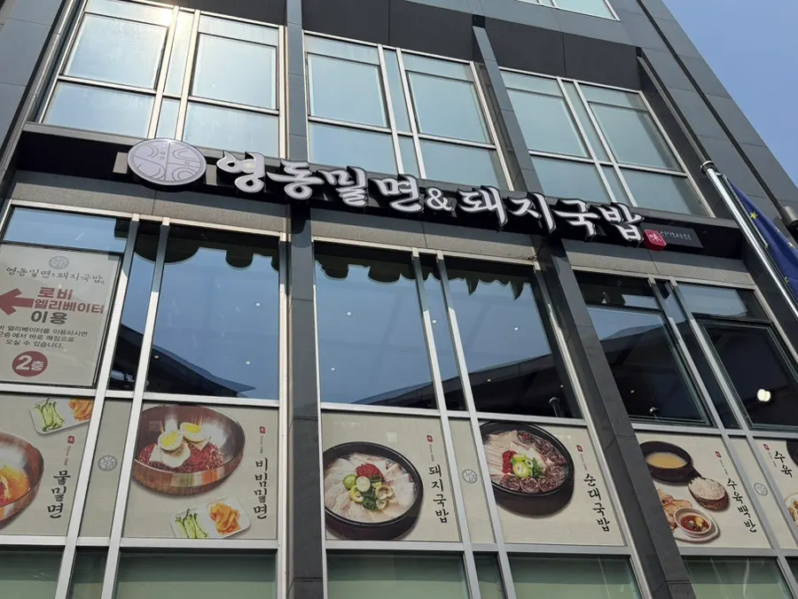Building exterior with a convenience store on the 1st floor and Yeongdong Milmyeon & Dwaeji Gukbap sign on the 2nd