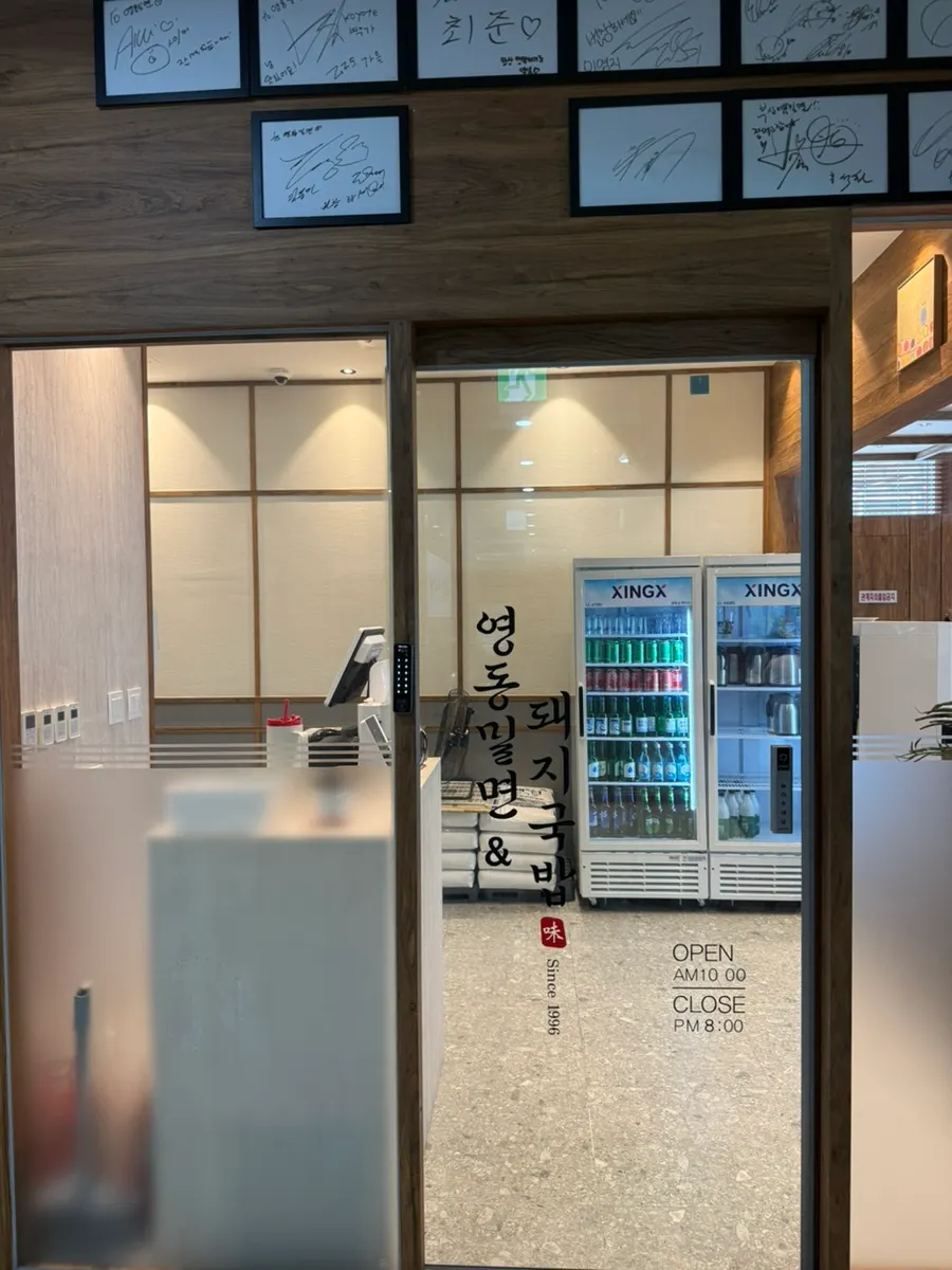 Business hours sign for Yeongdong Milmyeon & Dwaeji Gukbap Busan Station Branch