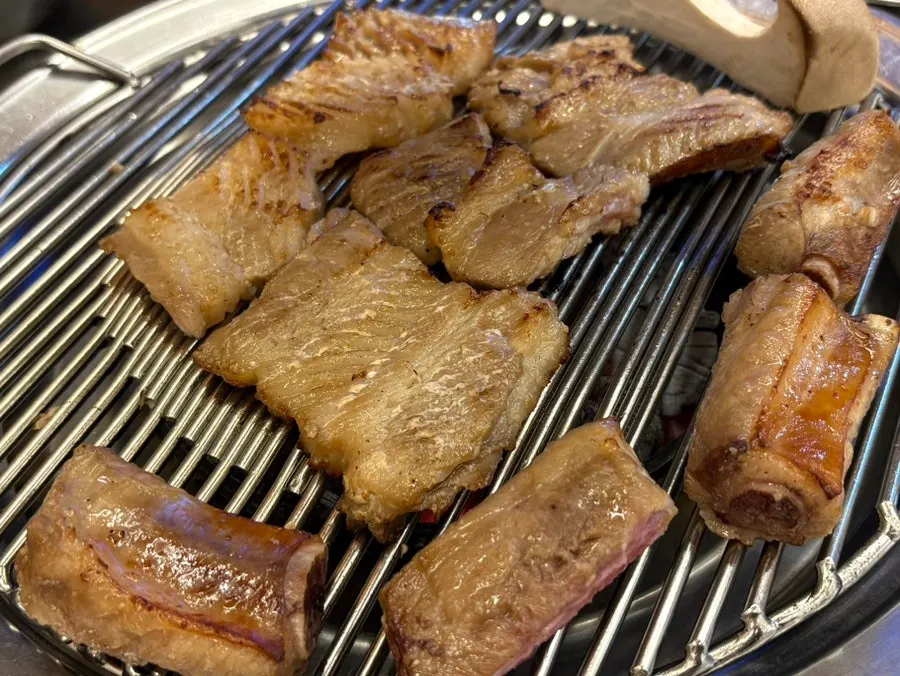 Seasoned pork ribs being flipped on the grill