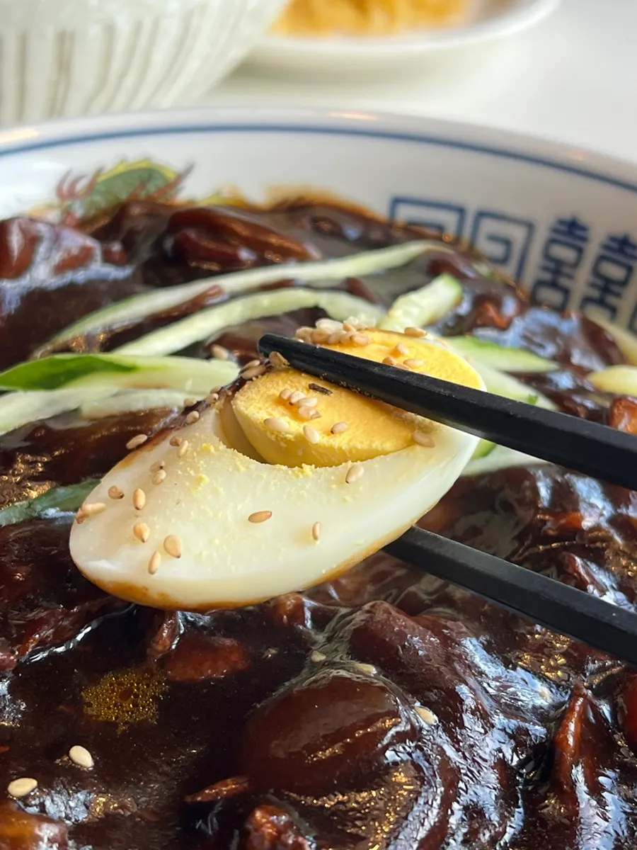 Half a soft-boiled egg on top of the jjajangmyeon