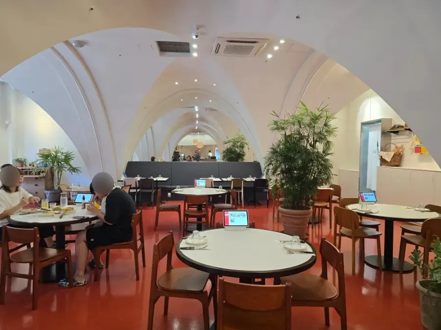 Hall with high ceilings, soft arched curves, and round tables
