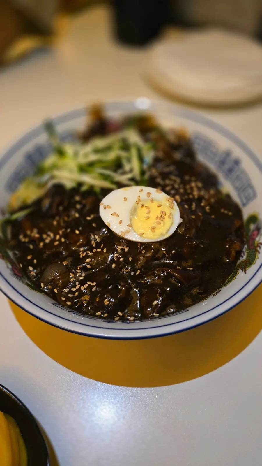 Bueok jjajangmyeon topped with cucumber, egg, and sesame seeds