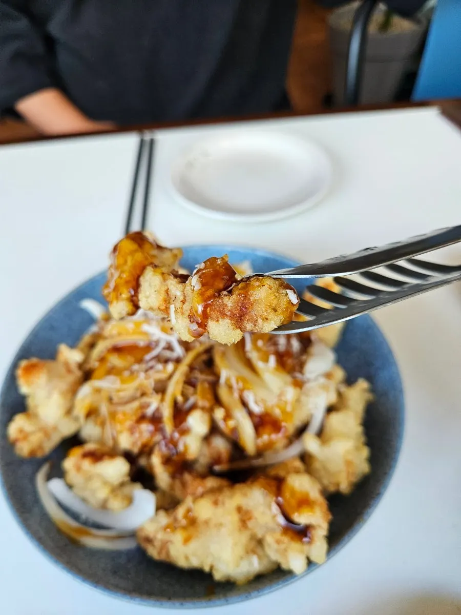 Chopstick lifting a bite of jjajang mixed with burst poached egg