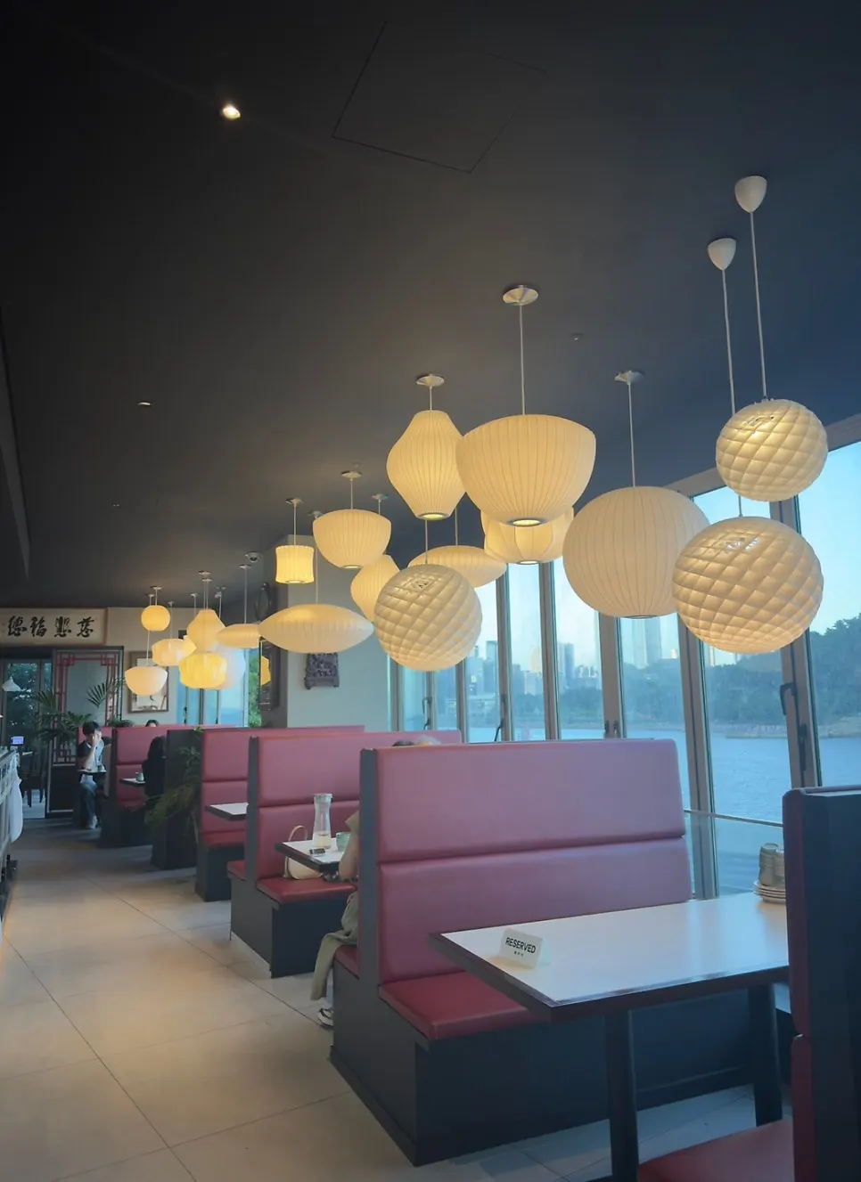 Dining hall with red-accented seating and a sea view through the windows