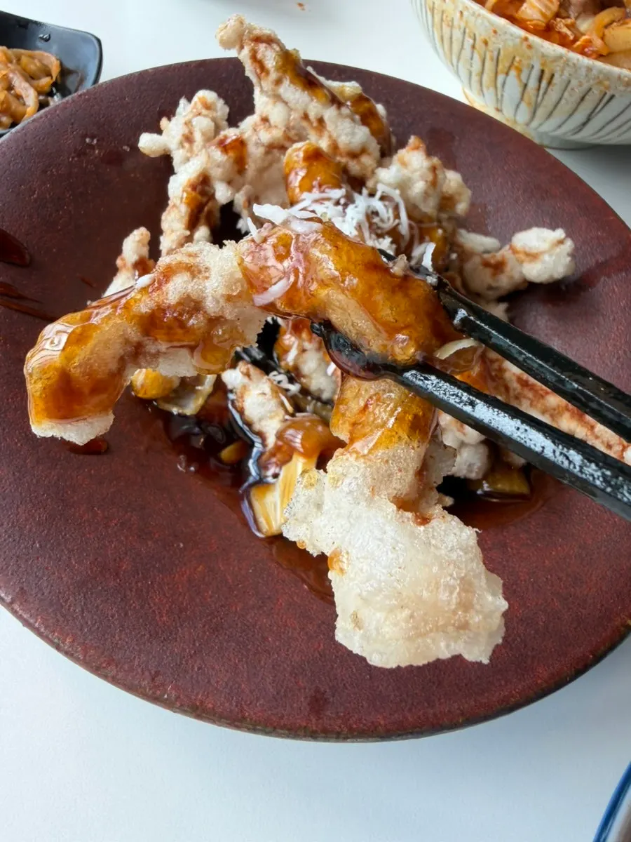 A piece of tangsuyuk dipped in black vinegar sauce
