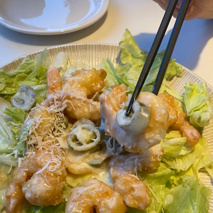 Close-up of fried shrimp topped with cream sauce and jalapeño