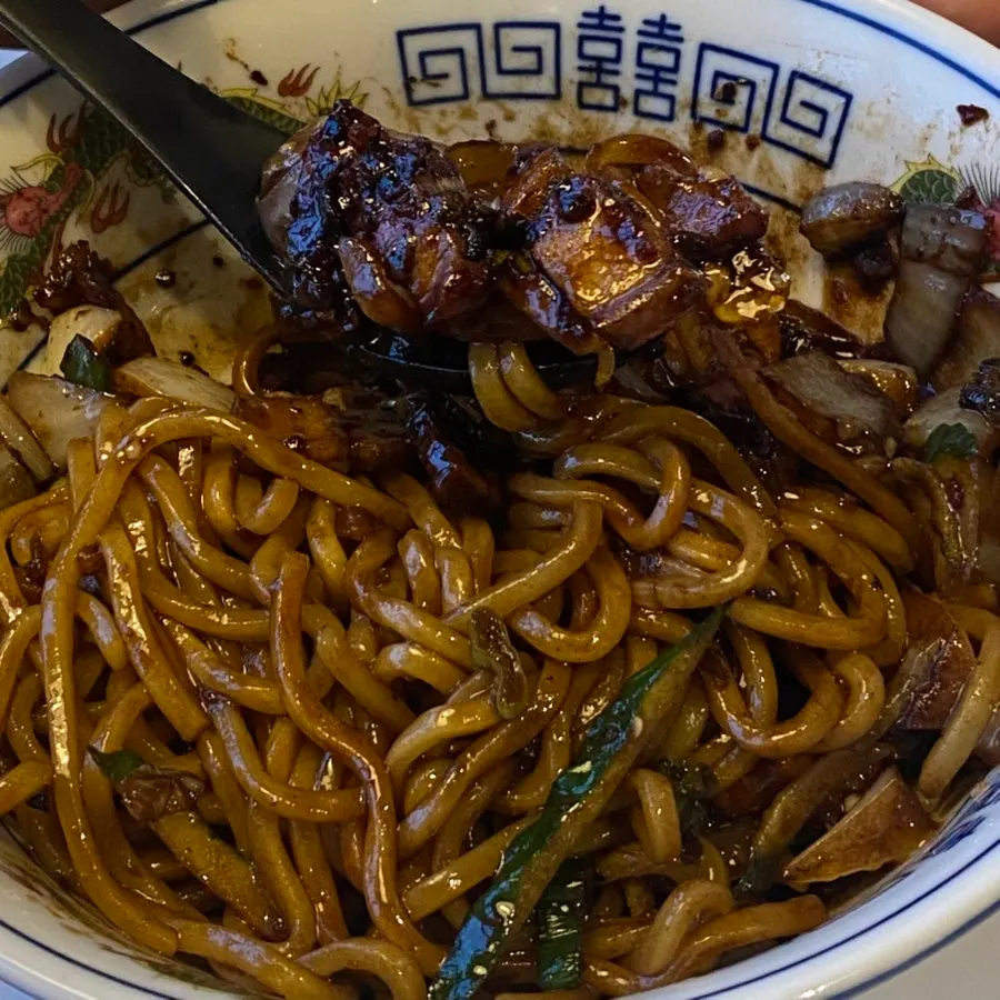 Noodles coated in jjajang sauce with pork belly