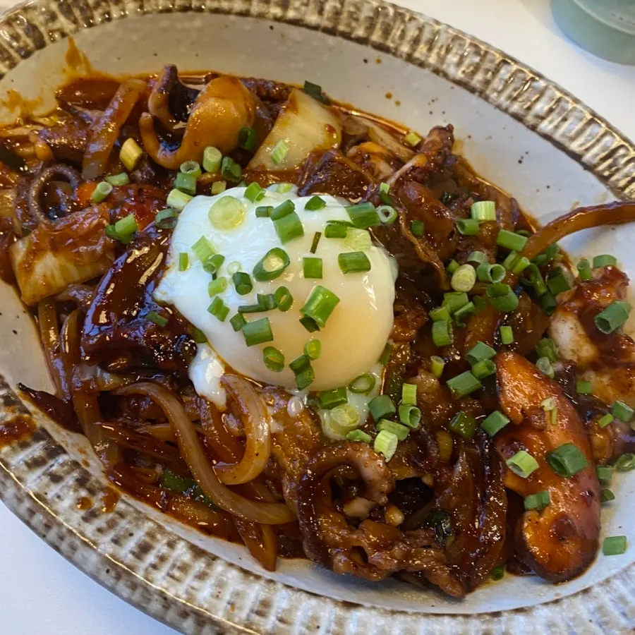Spicy octopus rice bowl topped with a poached egg