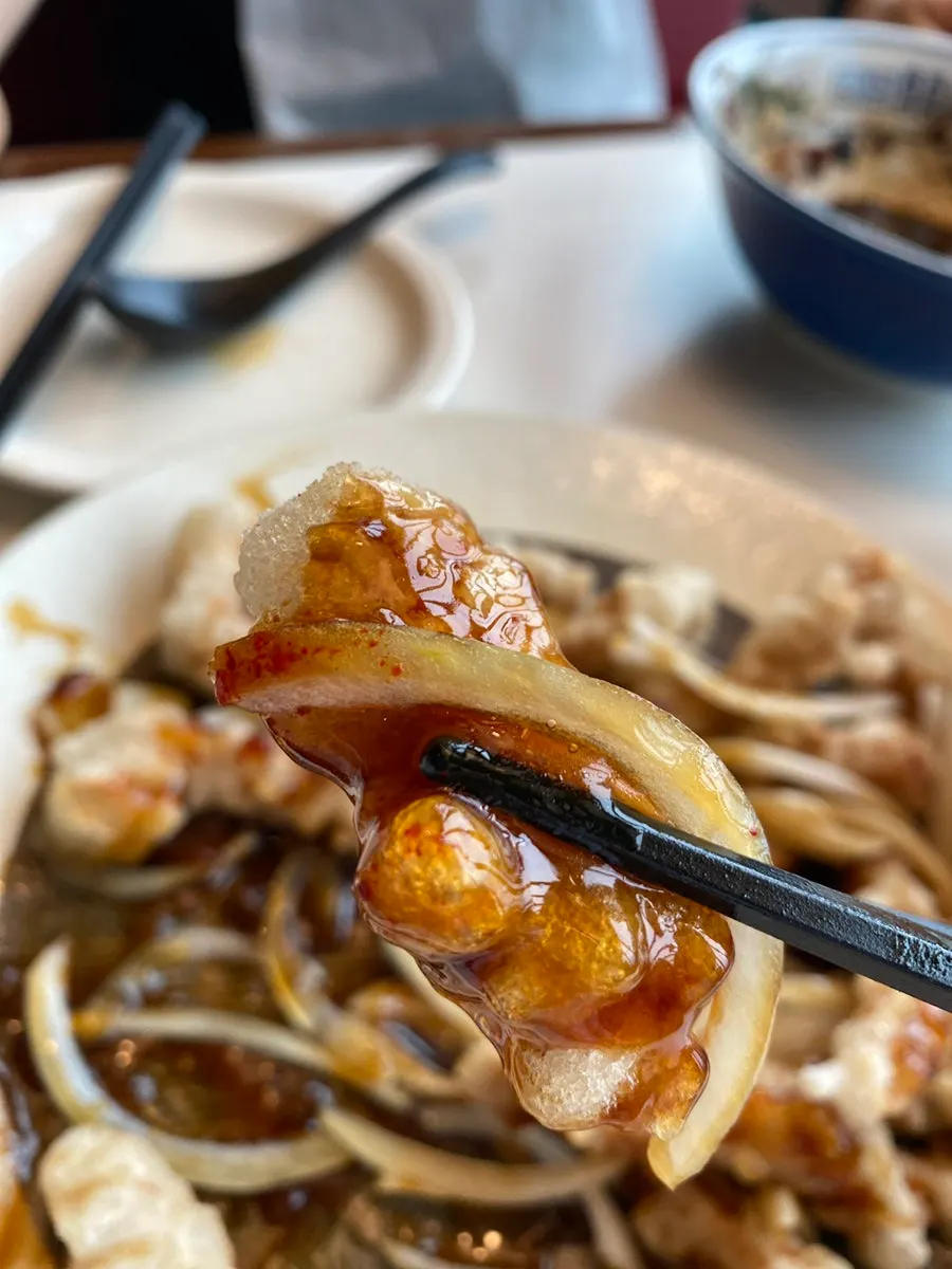 A piece of tangsuyuk coated in black vinegar sauce