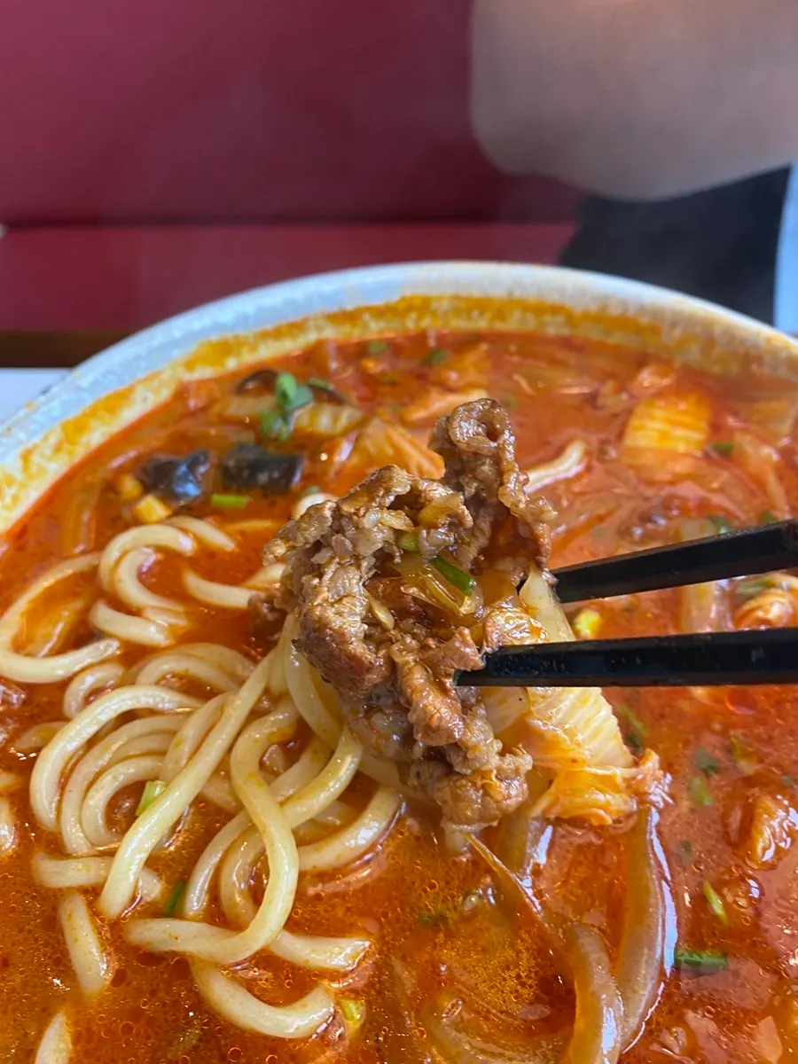 Lifting up jjamppong noodles and toppings