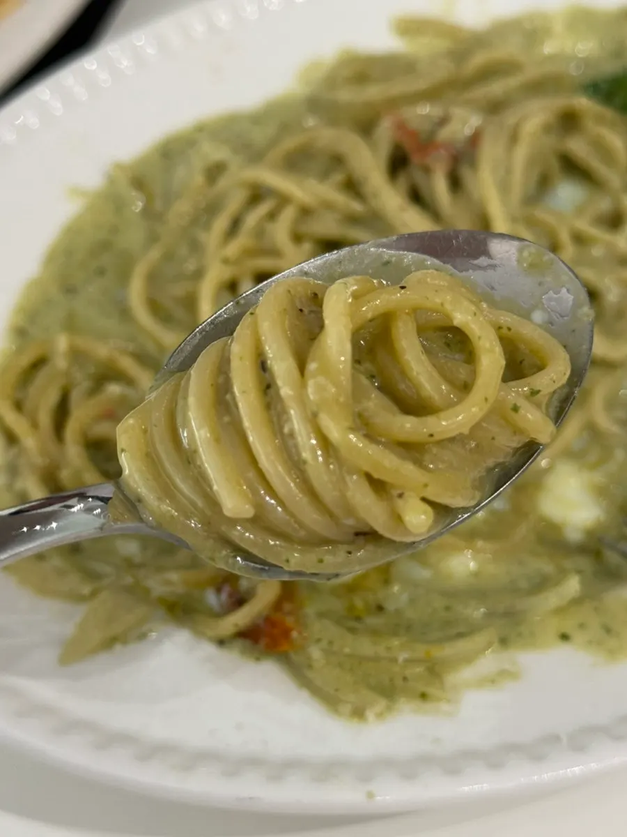 Basil pesto cream pasta topped with an egg yolk