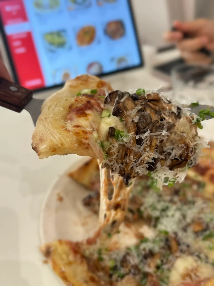A slice of truffle mushroom pizza showing the crust end