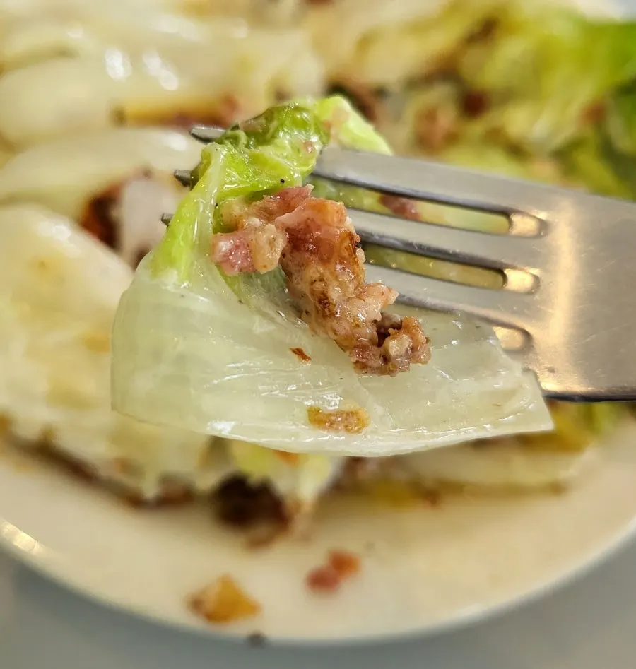 Grilled napa cabbage topped with bacon chips and cheese