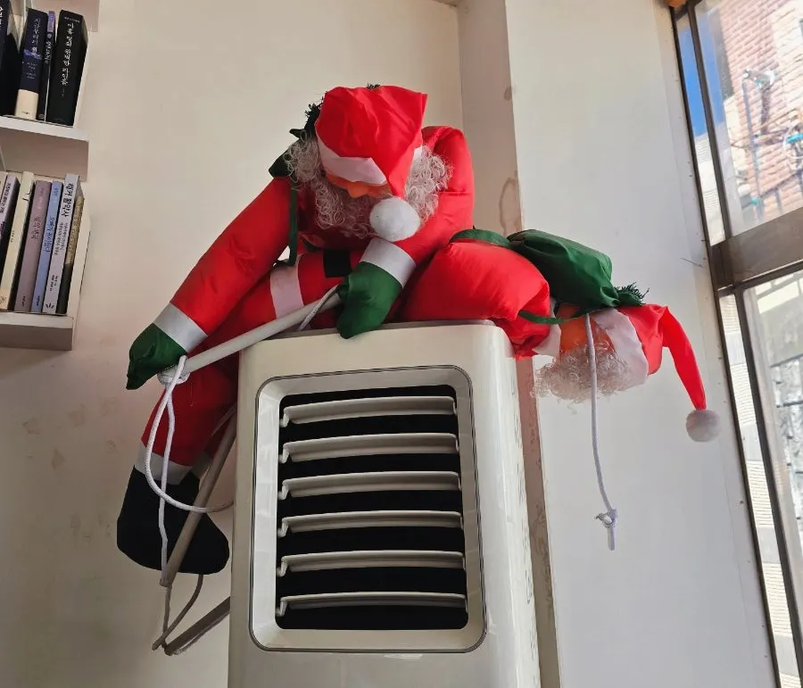 A Santa doll placed on top of the air conditioner