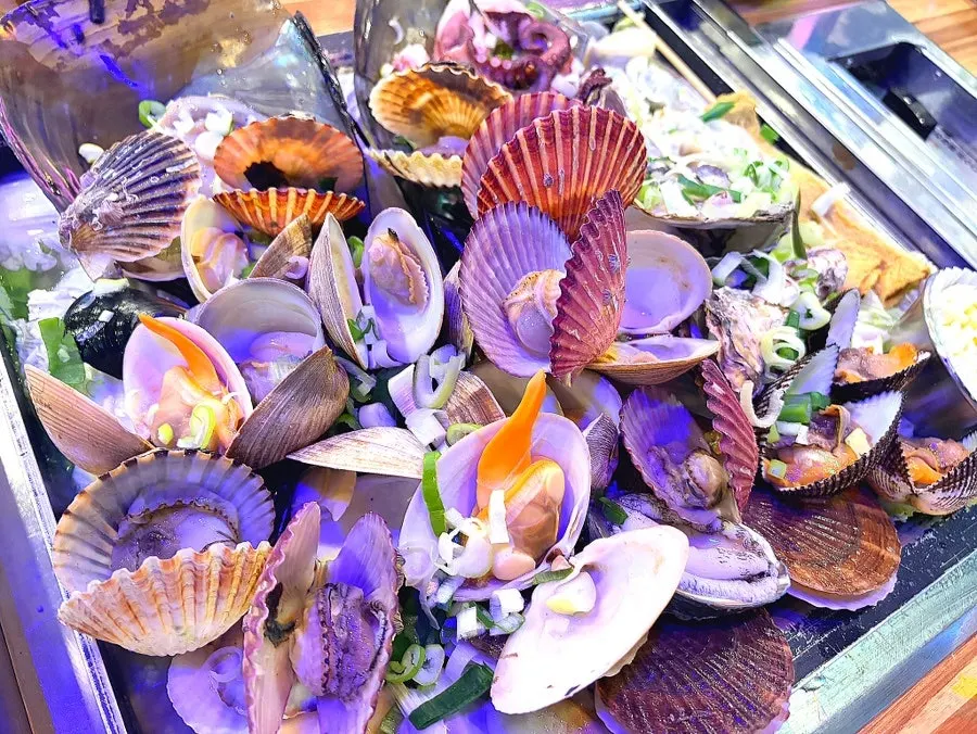 A massive tray of clam hot pot with broth arriving at the table