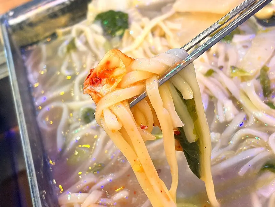 Fresh knife-cut noodles added to the clam hot pot broth