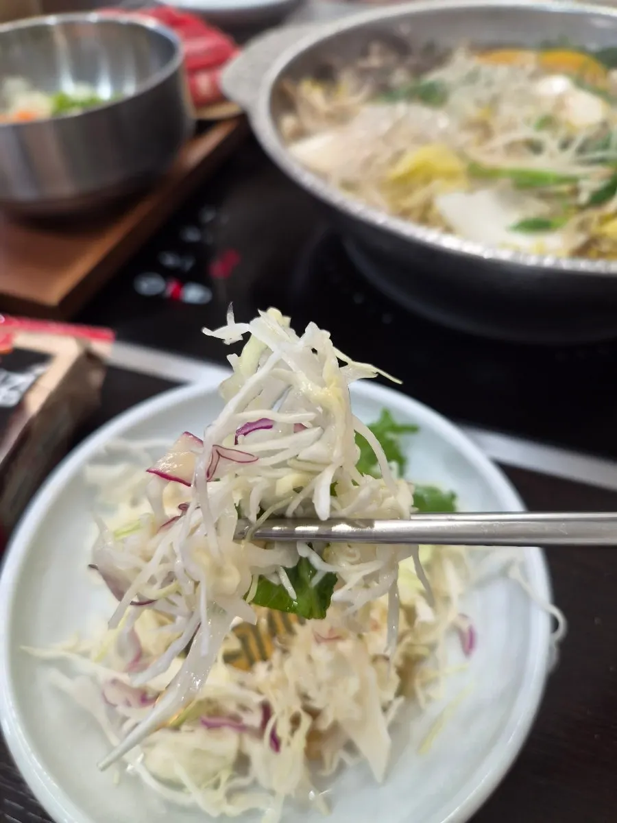 Self-serve bar with cabbage salad, broth, and sauces