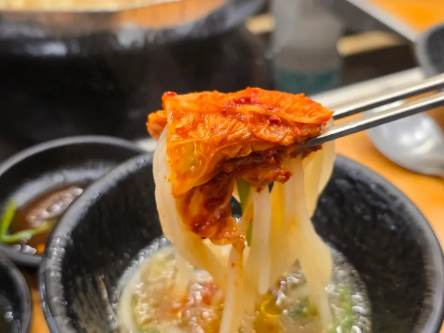 Bowl of kalguksu noodles topped with kimchi