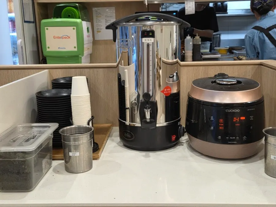 Self-serve corner by the counter with heotgae tea and rice refills