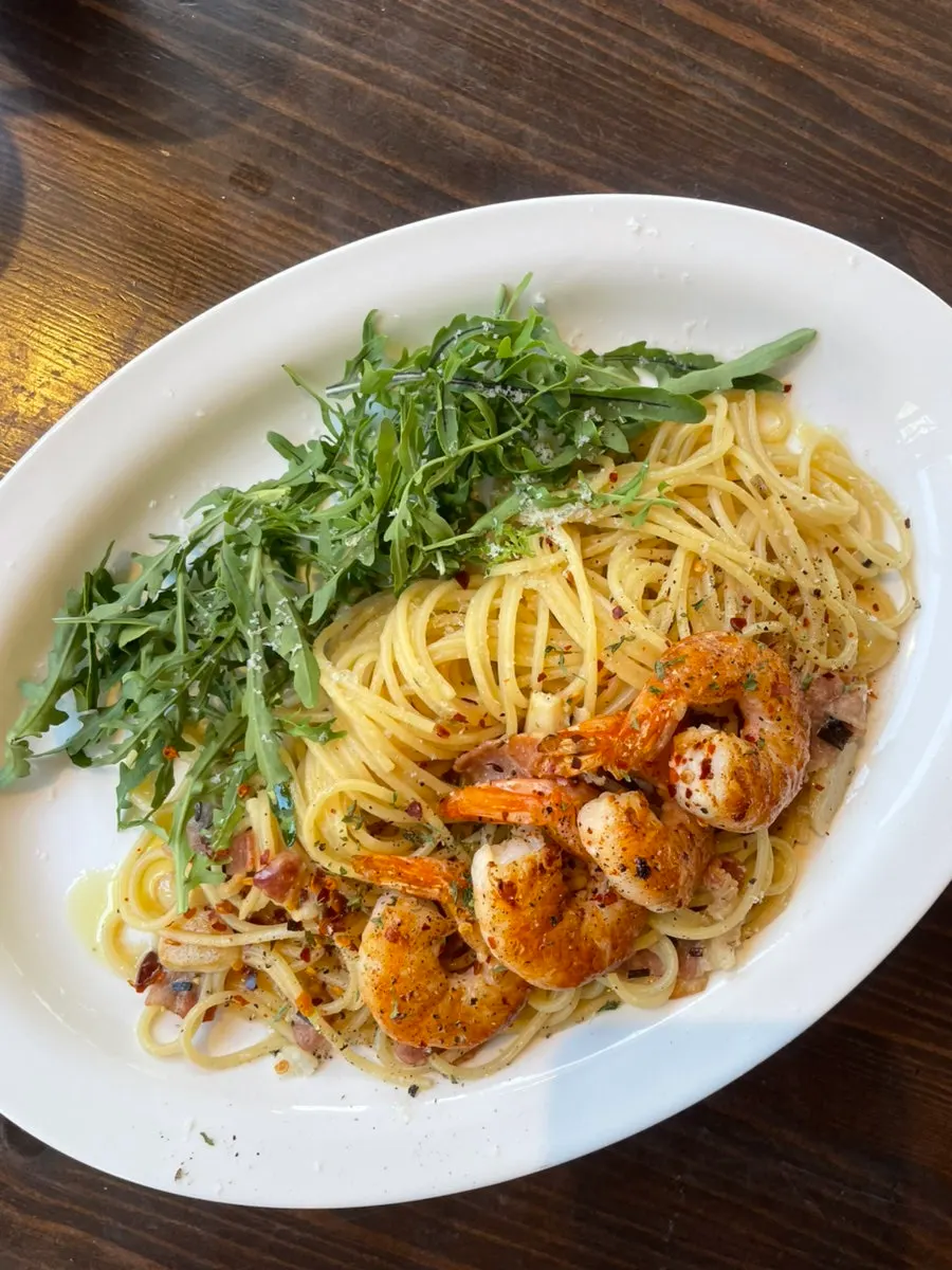 Close-up of anchovy bacon pasta topped with arugula