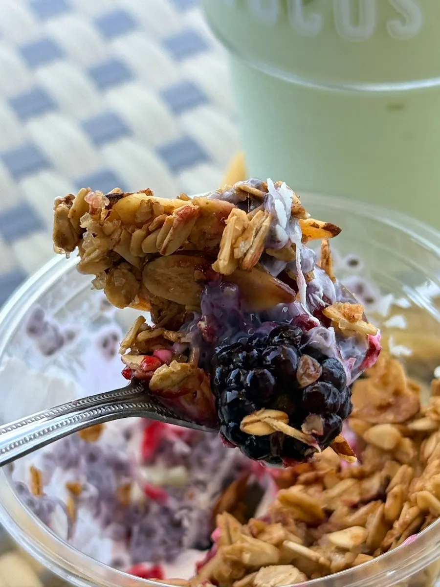 Spooning granola from the Greek yogurt bowl