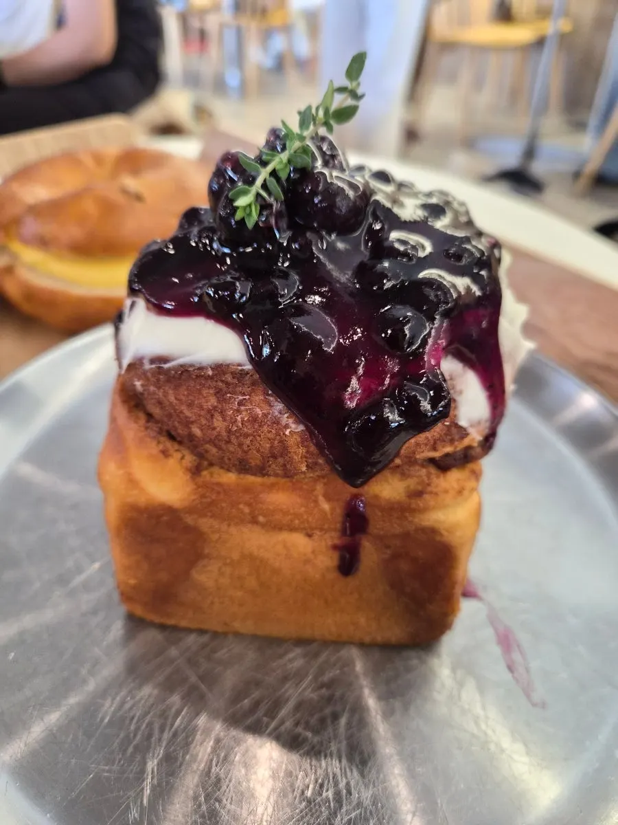 Cinnamon roll topped with blueberry jam and cream cheese