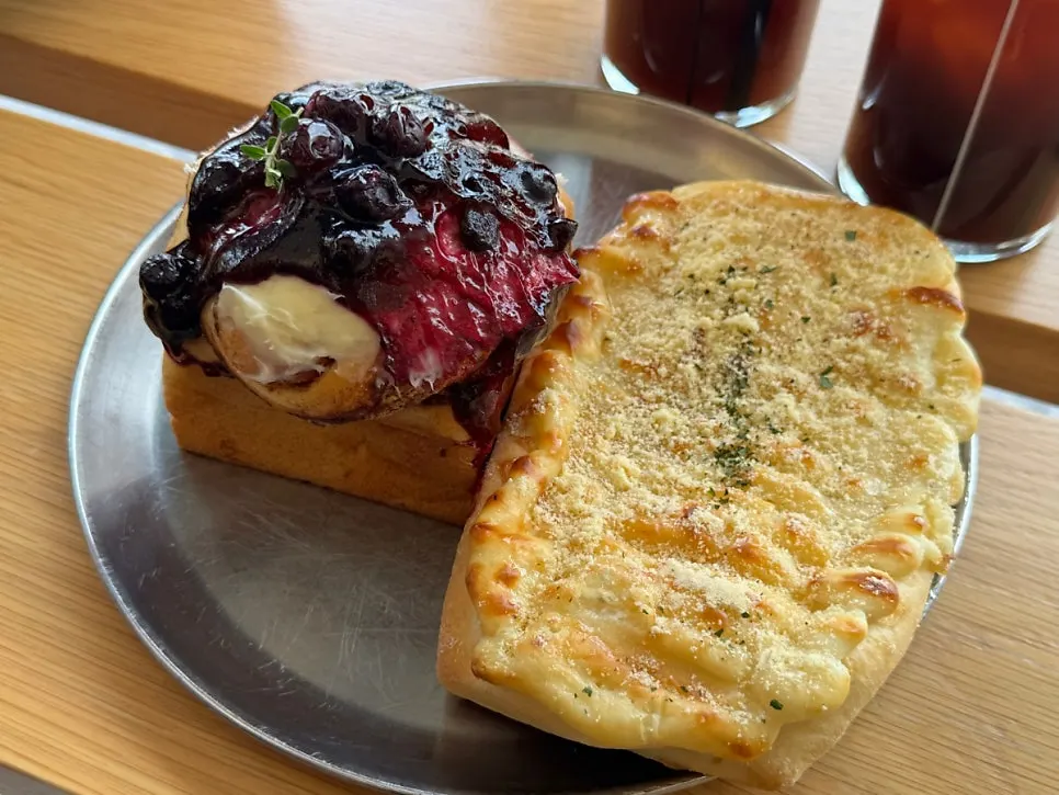 Square cinnamon roll topped with cream cheese and blueberry compote