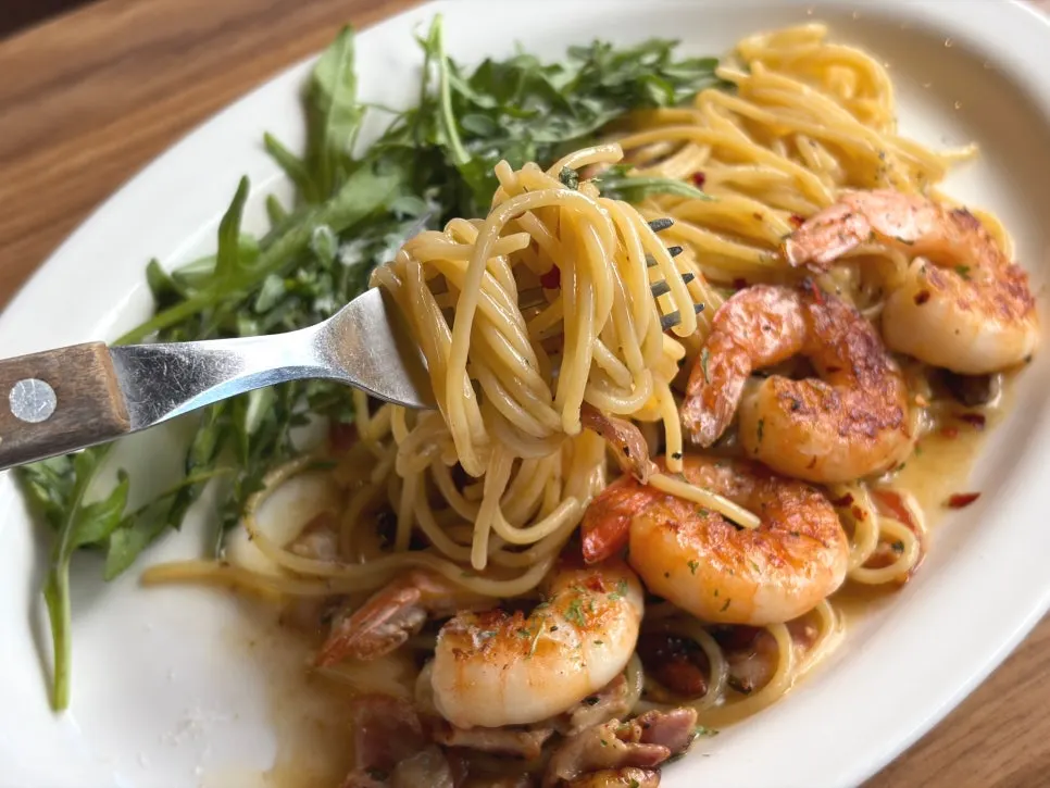 Close-up of anchovy bacon pasta topped with shrimp