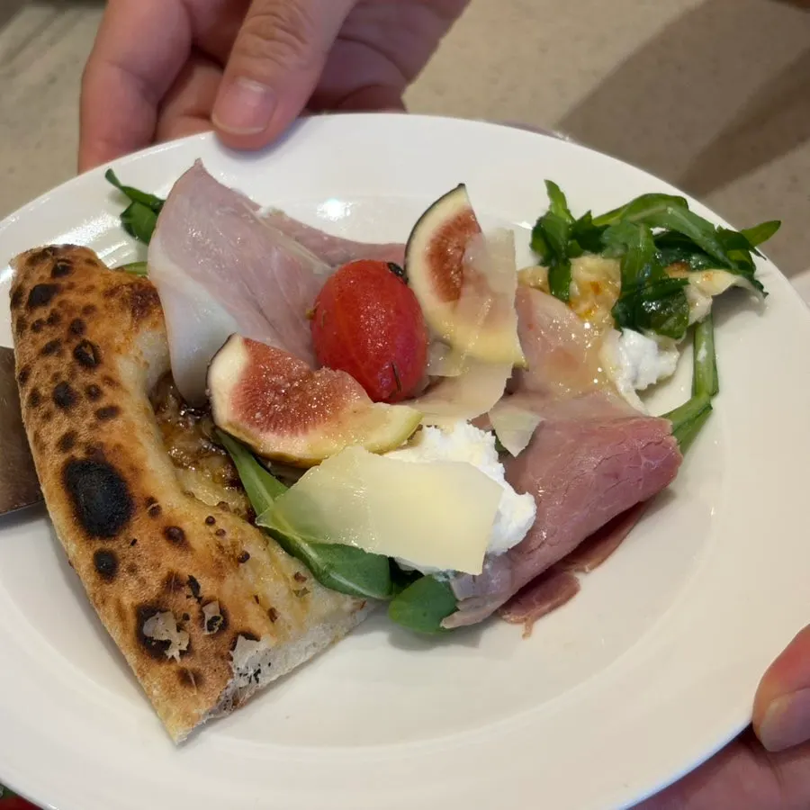 Pizza slice topped with ricotta cheese and jamón