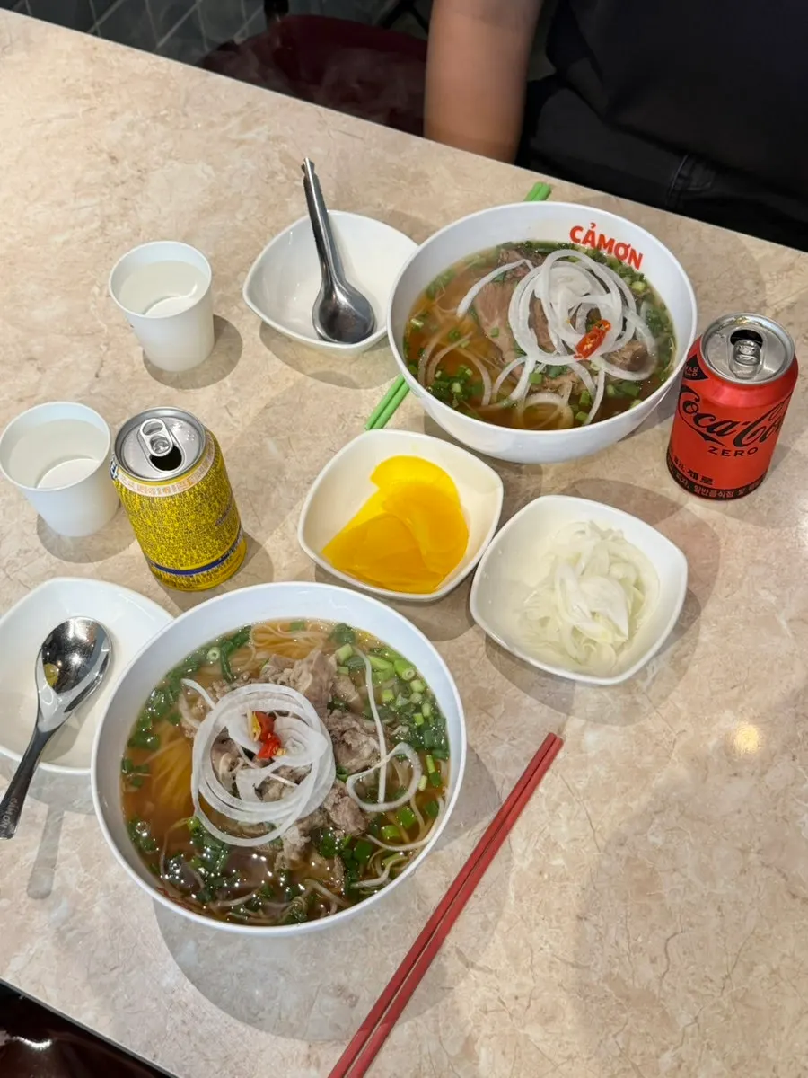 Table spread of two bowls of pho and fried chicken wings
