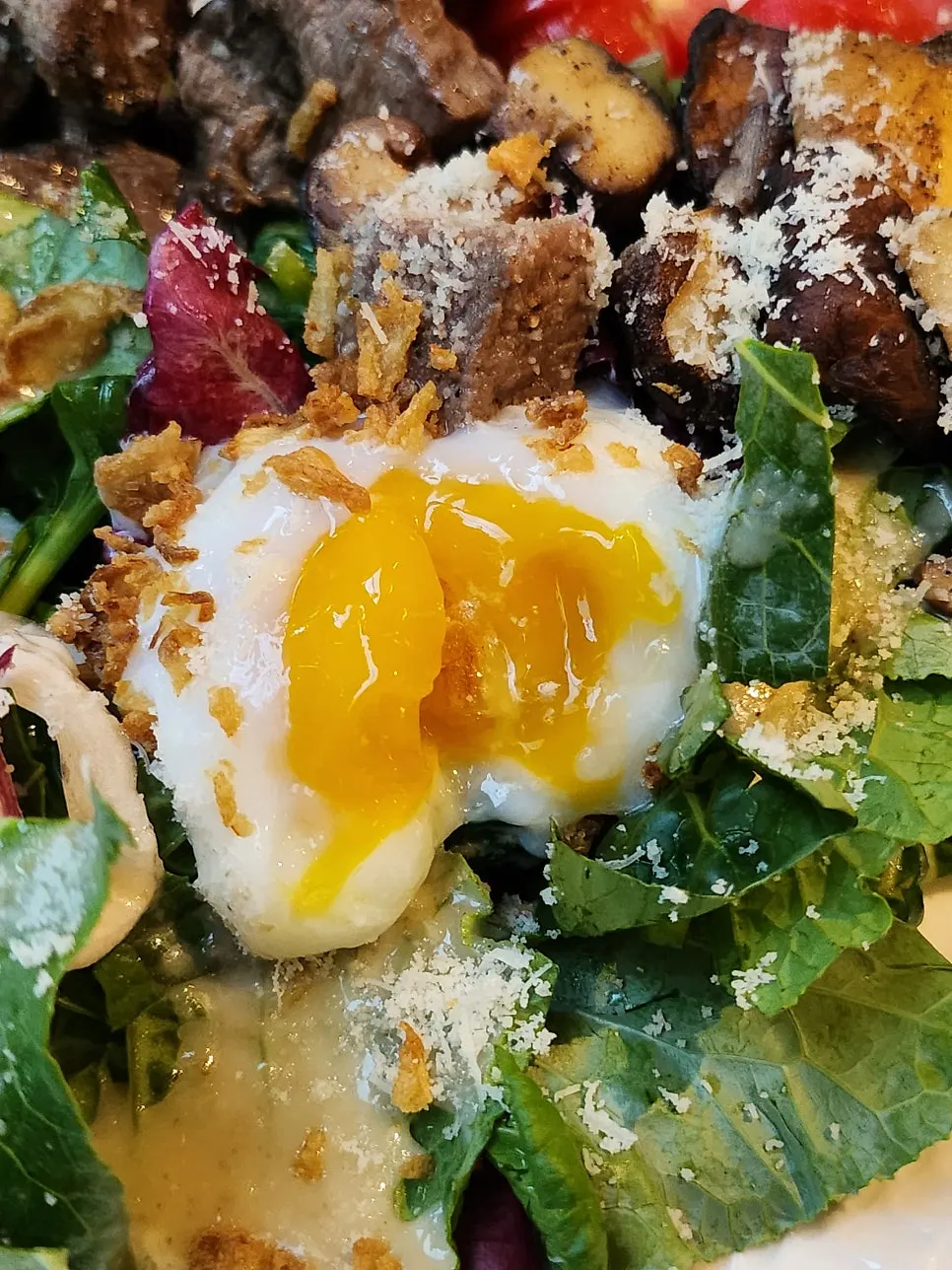 A bite of beef mushroom salad with broken egg yolk