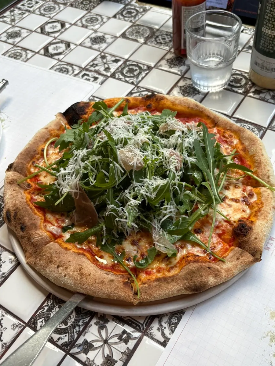 Close-up of wood-fired pizza piled with rocket