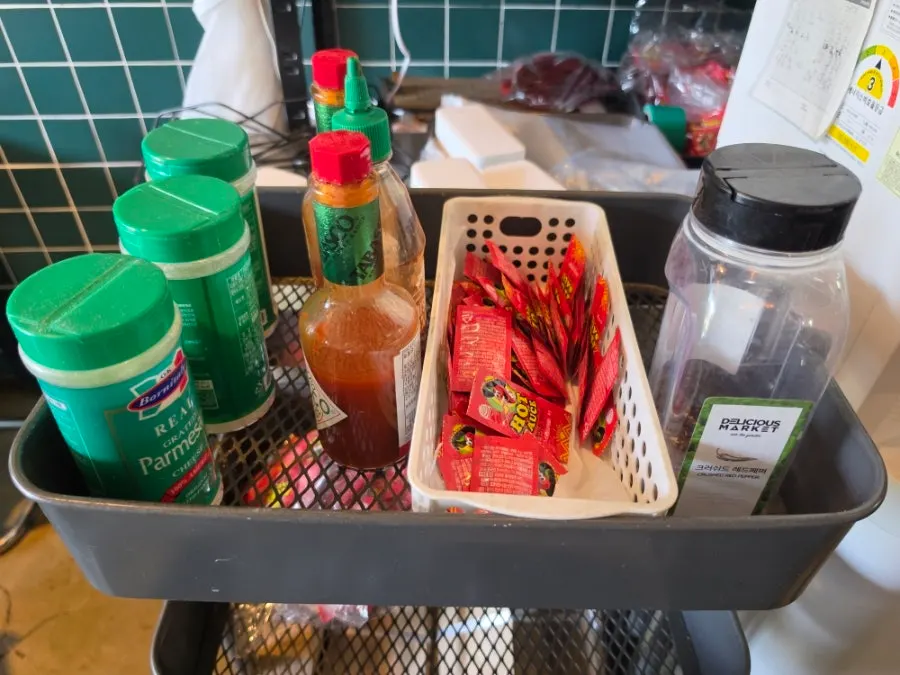 Parmesan cheese and hot sauce at the self-serve bar