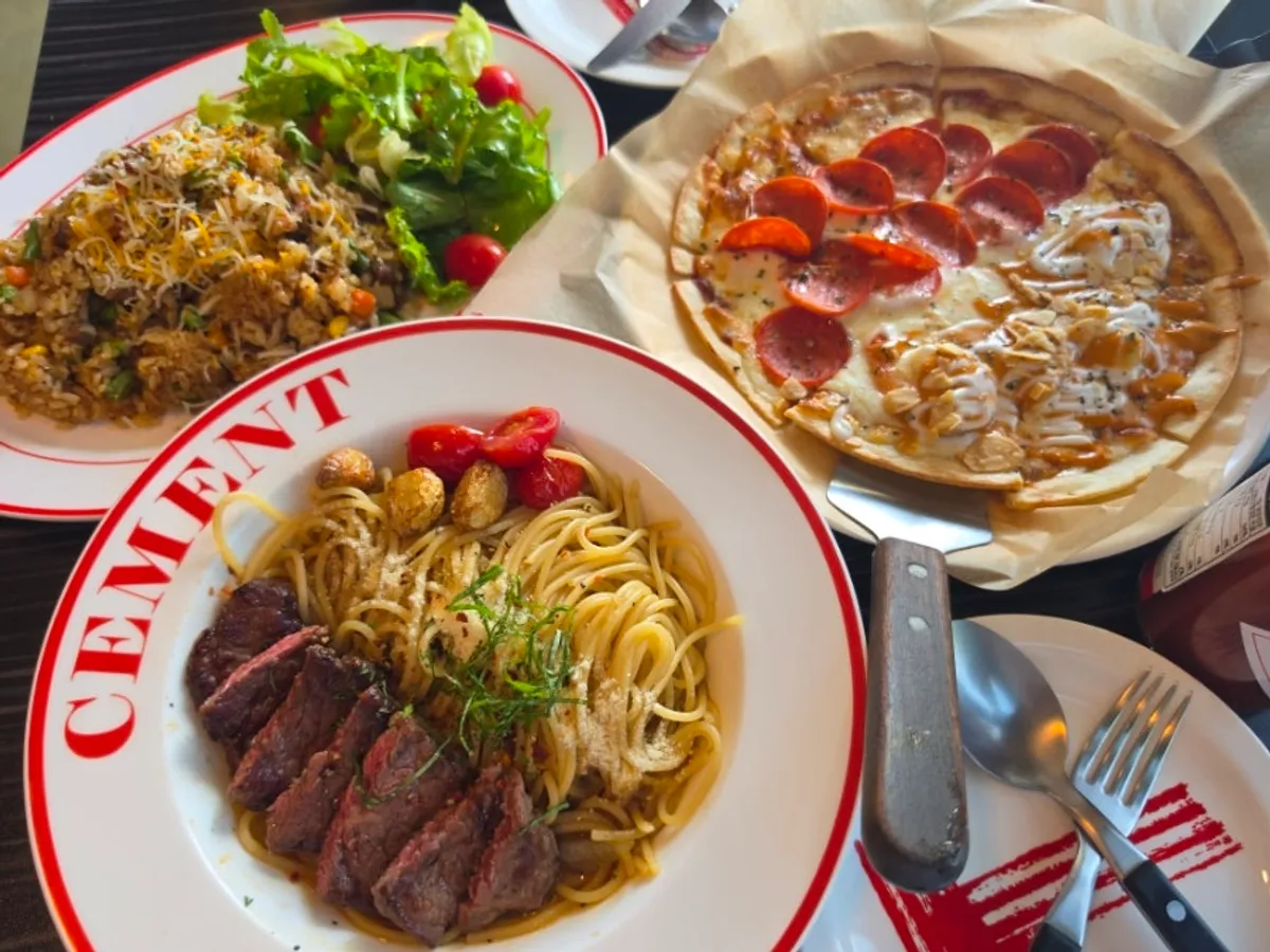 Table for two packed with pasta, half-and-half pizza, and pilaf