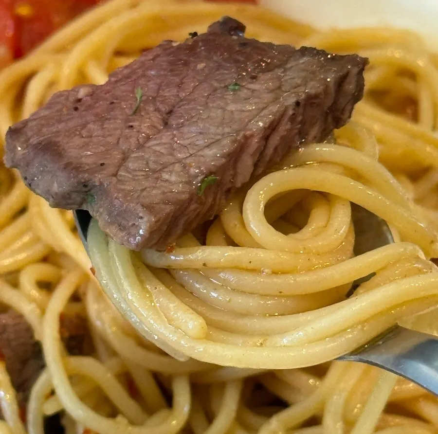 A piece of beef striploin placed on the pasta