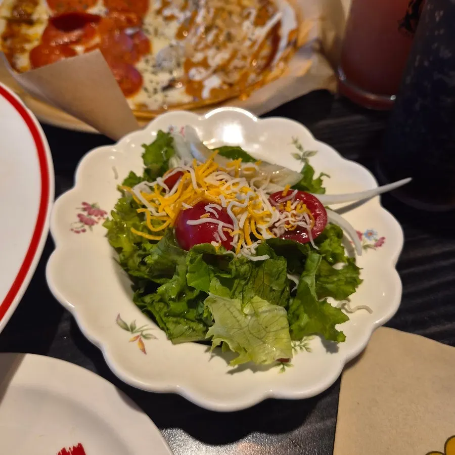 A plate of salad served alongside the pizza