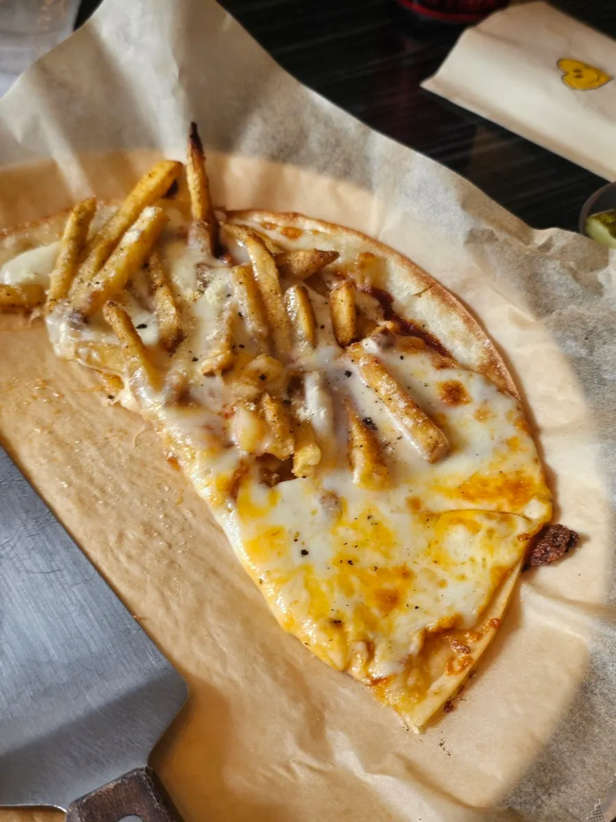 A slice of the thin-crust half-and-half pizza