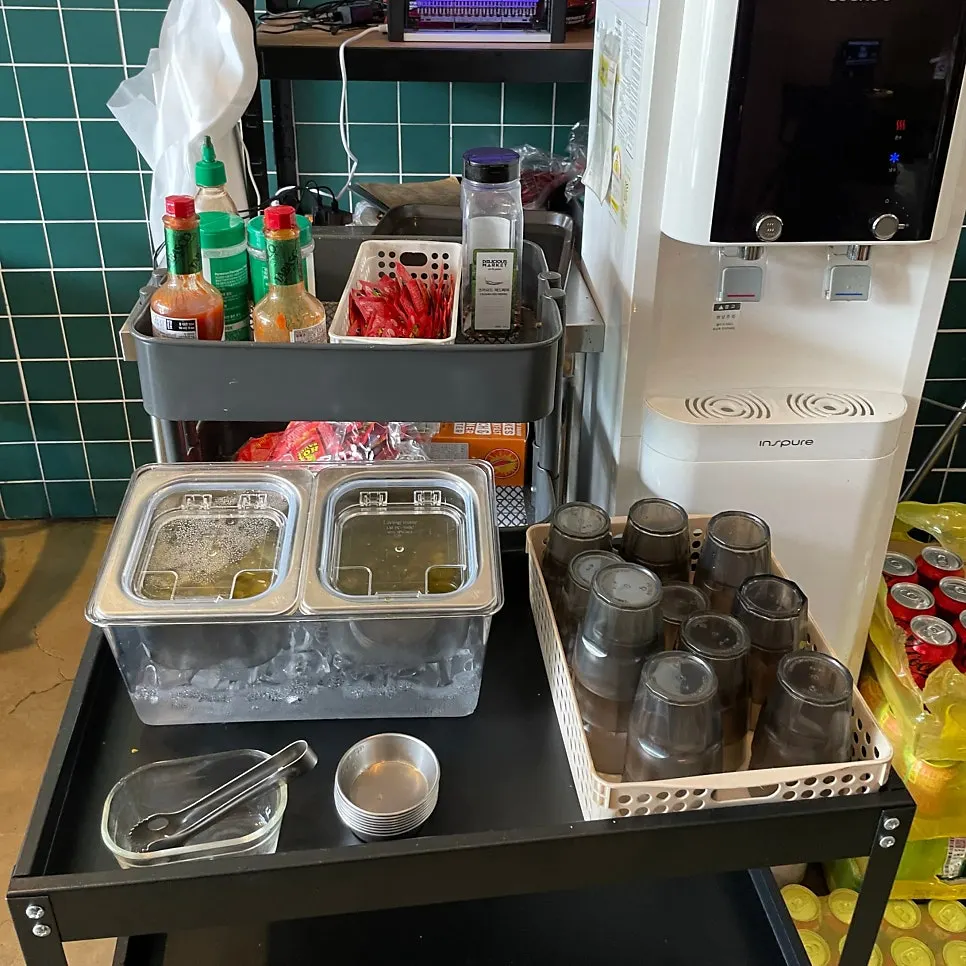 Self-serve corner with water, pickles, and sauces