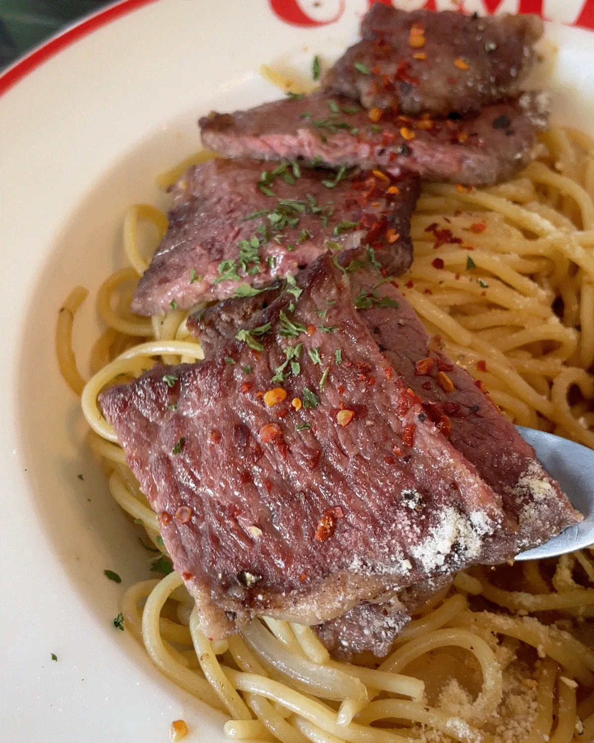 Close-up of golden-grilled chuck flap steak over oil pasta