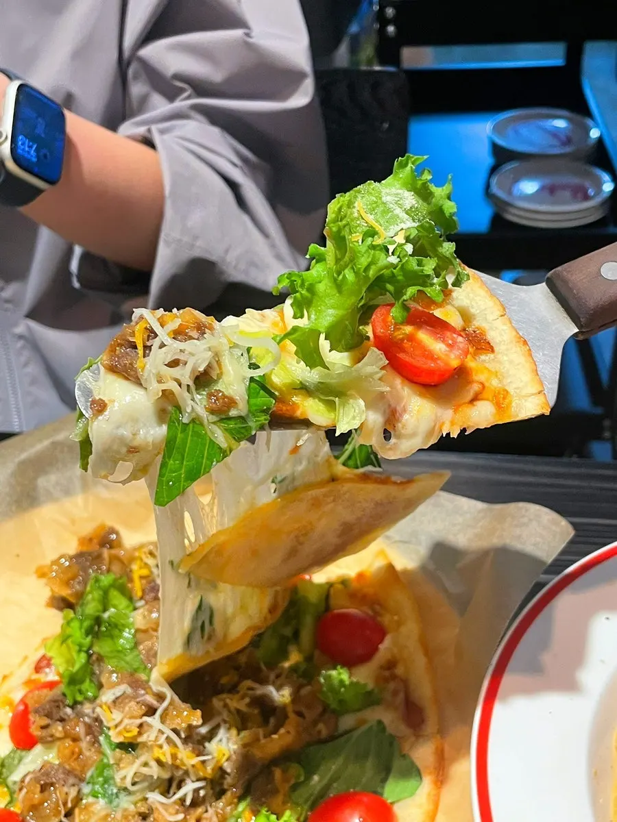 A slice of thin-crust bulgogi salad pizza