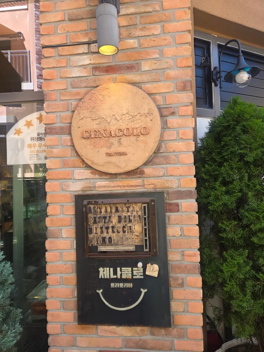 Entrance of Cenacolo with green plants and a wooden OPEN sign