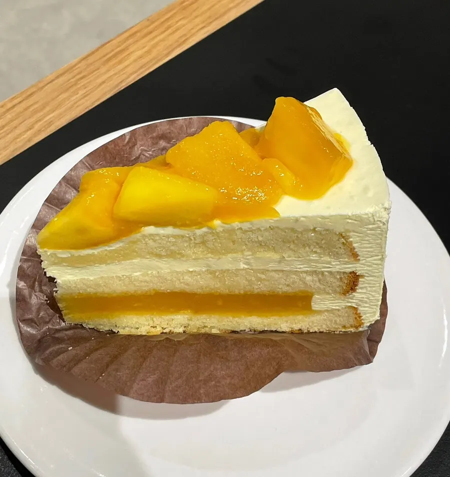 A plate of mango cake with yellow cream