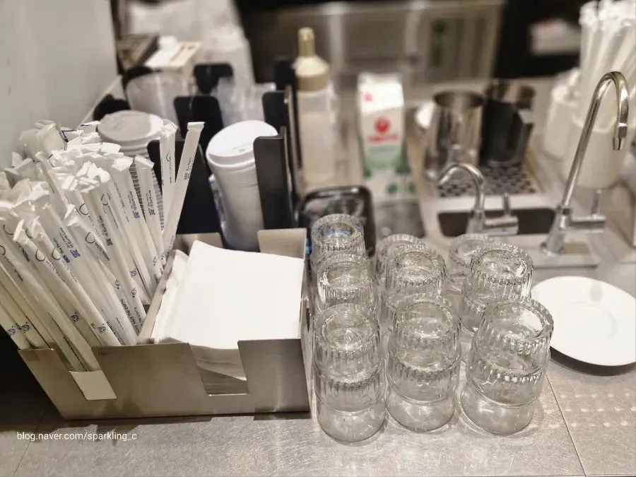 Self-service bar with water, cups, napkins, and straws
