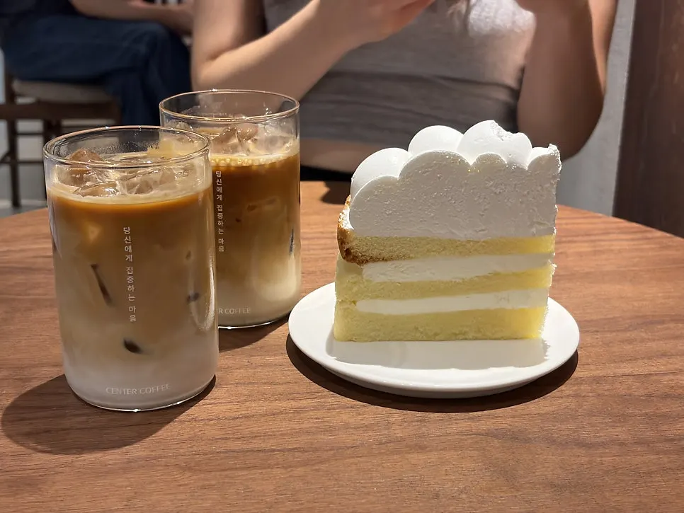 테이블에 놓인 라떼 두 잔과 생크림 케이크