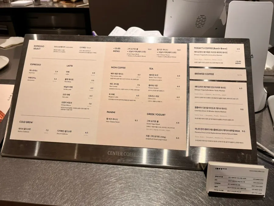 Counter menu board listing espresso, lattes, and brewed coffee