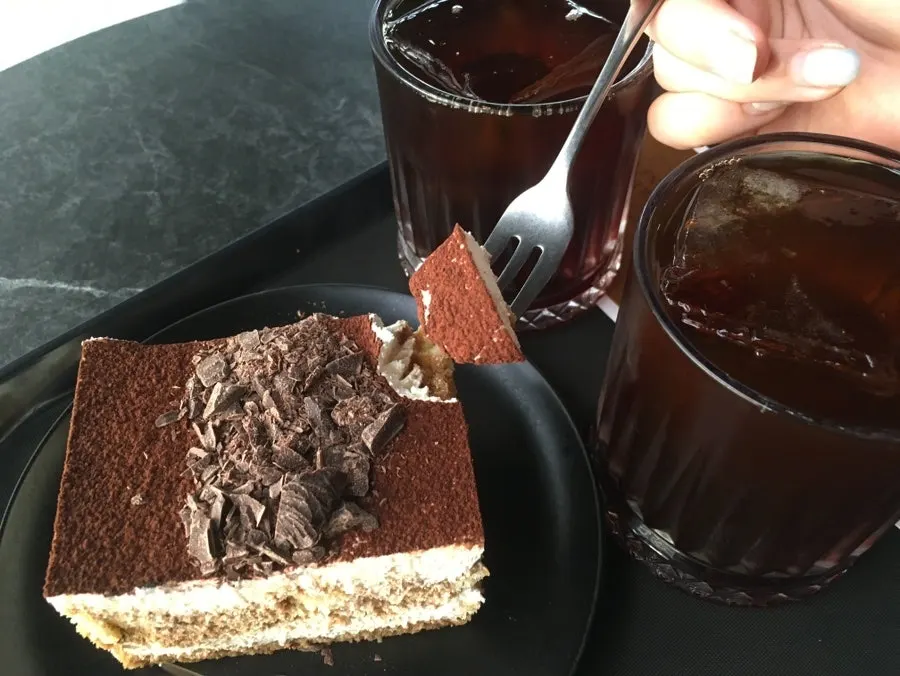 A plate of tiramisu served alongside coffee