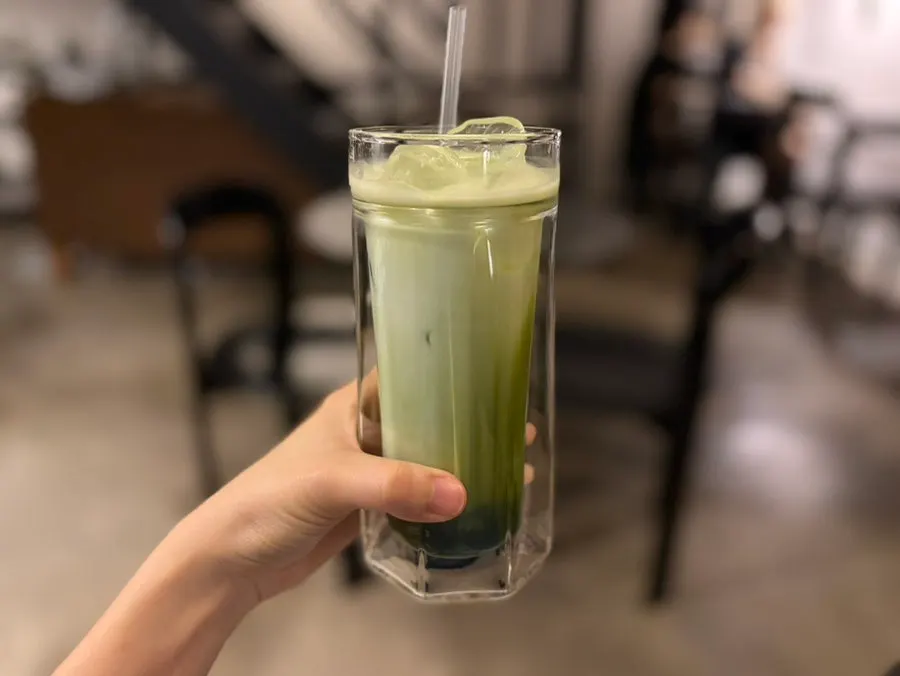 A glass of matcha latte with matcha and milk mixed in