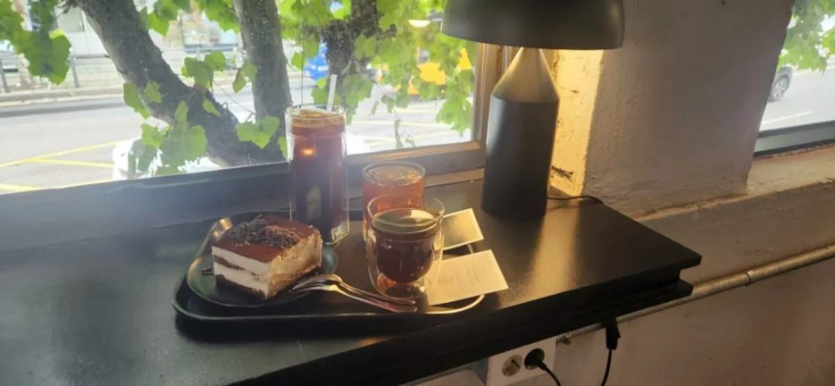 Iced drip coffee with a square ice cube alongside tiramisu